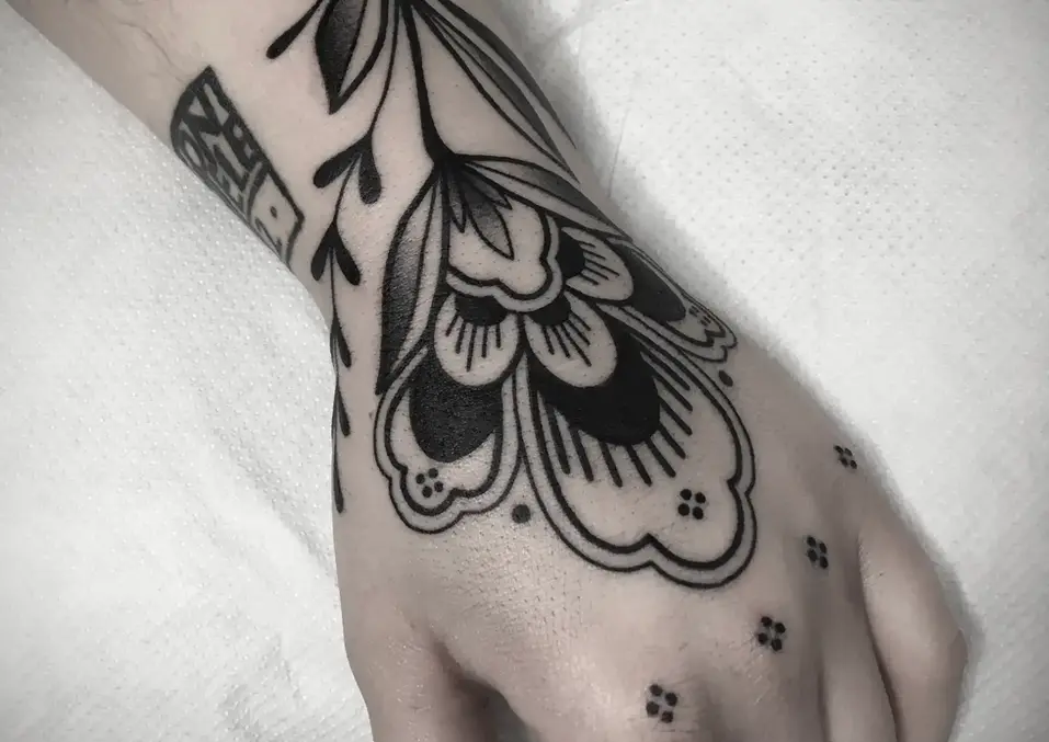 Schwarzes florales Tattoo auf dem Handrücken und Handgelenk.