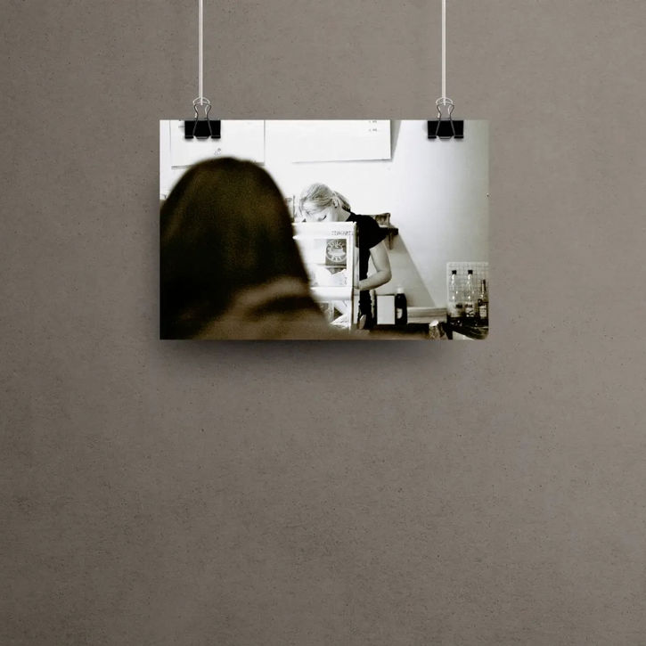 Person arbeitet hinter einer Theke; eine weitere Person ist unscharf im Vordergrund.