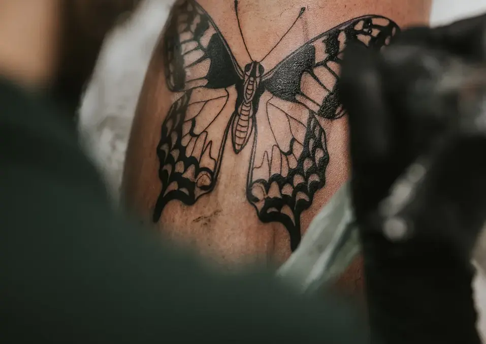 Detailaufnahme eines Schmetterling-Tattoos auf dem Rücken.