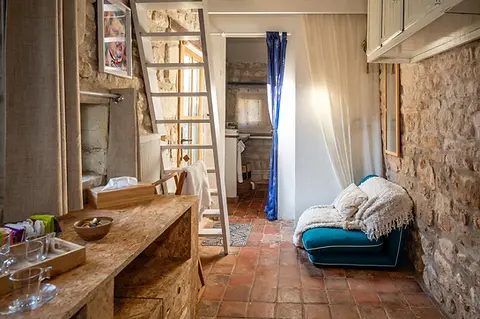 Balzac room with natural stone walls, ladder to mezzanine and seating area