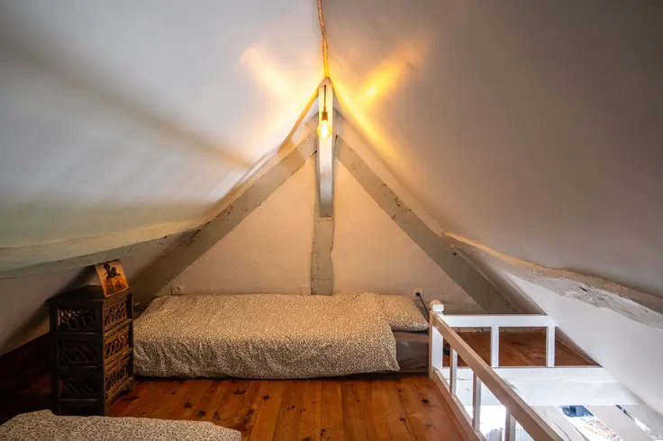 Eenpersoonsbedden onder schuin dak met houten vloer en dakstructuur
