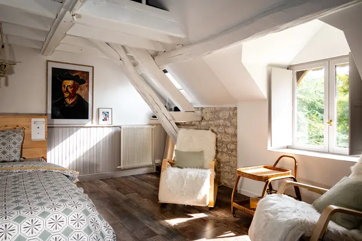 Slaapkamer Rabelais met zichtbaar houten dakgebinte, zetel en raam met groen uitzicht