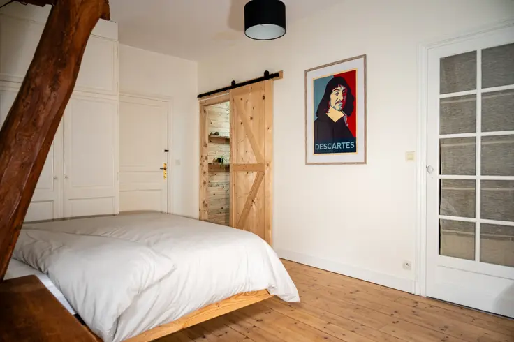 Descartes-kamer met bed, houten schuifdeur en wanddecoratie

