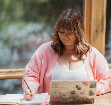 Nicole sitting in a sunroom writing down notes in her notebook.