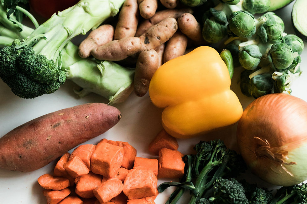 Peppers, broccoli, greens and sweet potatoes on a white table