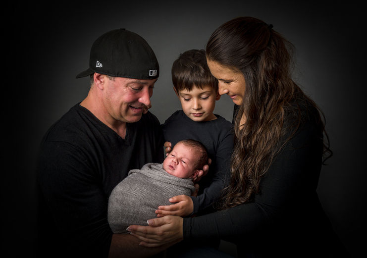 Familienshooting im Studio mit dunklem Hintergrund und Baby