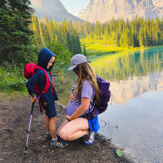 hiking mom pregnant with son wearing hoodie by lake