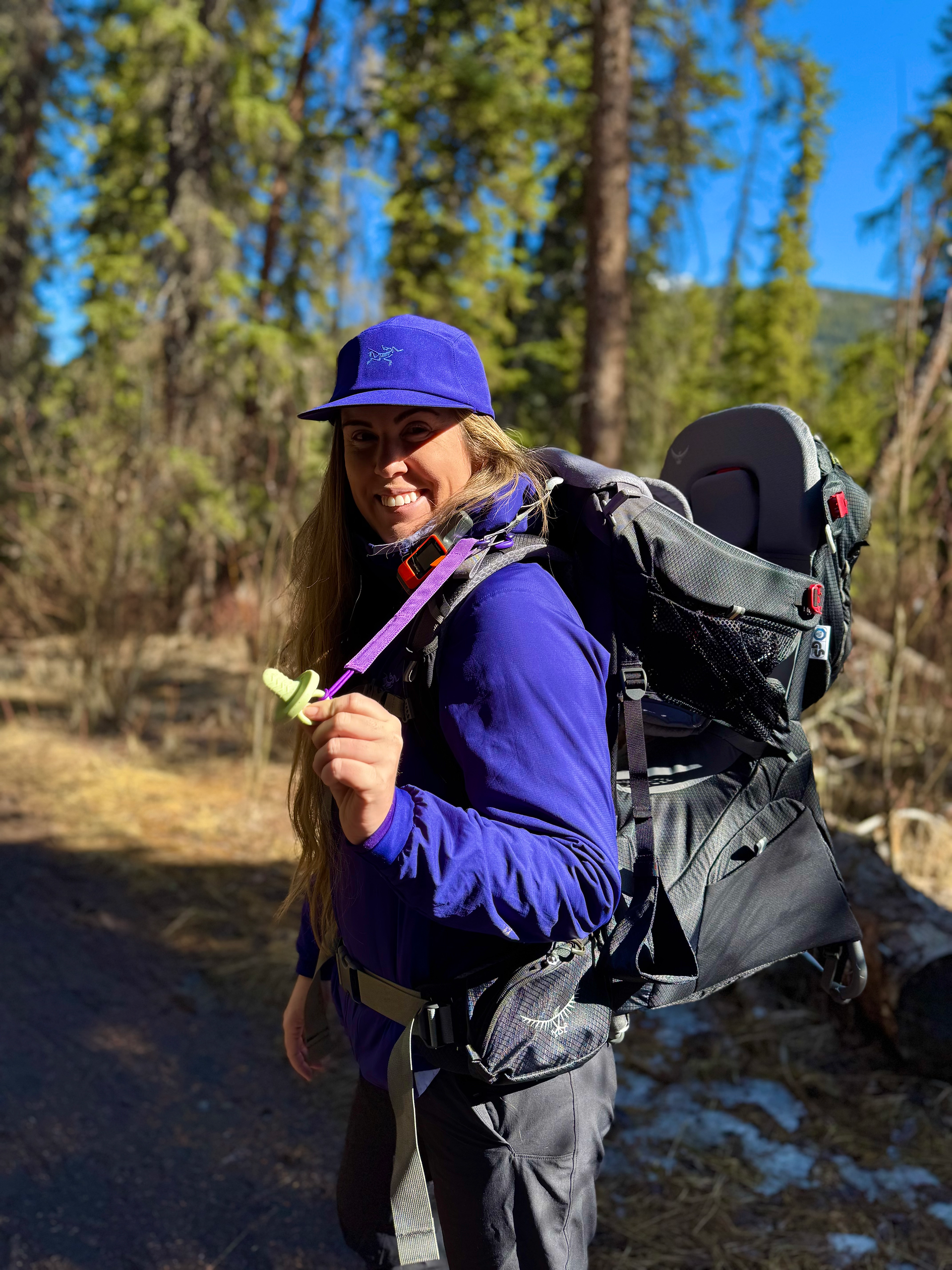 an outdoor mom holding a soother on the end of a trail tether