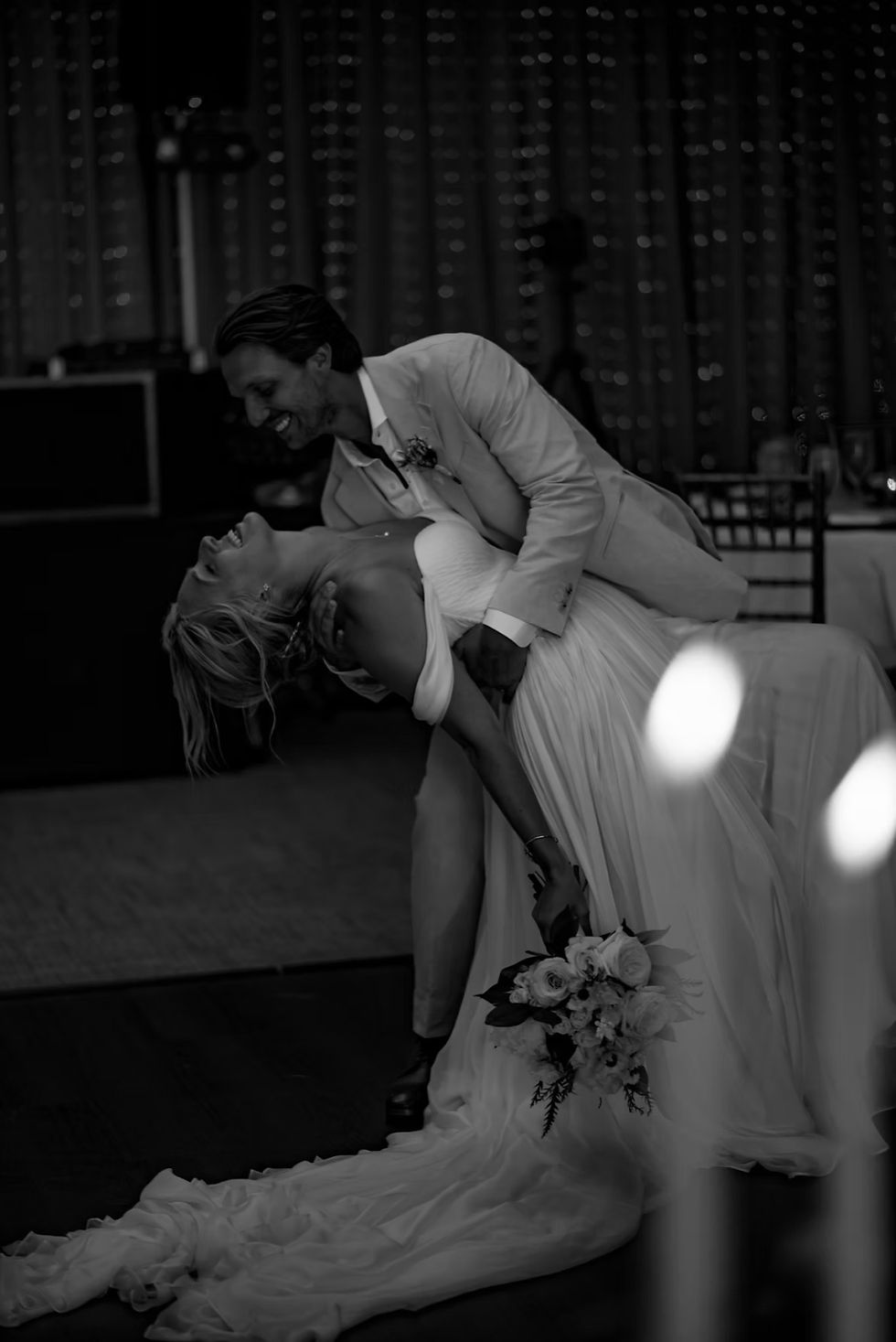 Bride and groom laughing together during a playful dip on the dance floor.