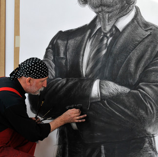 Valeriu Mladin in his studio, working on monumental drawings from the Political Bestiary series; documentary images taken over 12 years, capturing the working atmosphere, the scale of the studio, the creative process and the charcoal technique, with hybrid figures combining human bodies and animal heads.