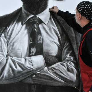 Valeriu Mladin in his studio, working on monumental drawings from the Political Bestiary series; documentary images taken over 12 years, capturing the working atmosphere, the scale of the studio, the creative process and the charcoal technique, with hybrid figures combining human bodies and animal heads.