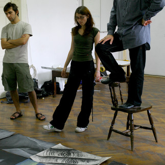 Profesorul și artistul Valeriu Mladin în dialog cu studenții săi din Departamentul Foto-Video al UNArte București. Fotografie care surprinde procesul de învățare prin desen, culoare și compoziție, în cadrul unei pedagogii bazate pe reflecție și experiment vizual. Professor and artist Valeriu Mladin in dialogue with his students from the Photo-Video Department at UNArte Bucharest. Photograph capturing the learning process through drawing, color, and composition, within a pedagogy grounded in reflection and visual experimentation.