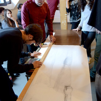 Profesorul și artistul Valeriu Mladin în dialog cu studenții săi din Departamentul Foto-Video al UNArte București. Fotografie care surprinde procesul de învățare prin desen, culoare și compoziție, în cadrul unei pedagogii bazate pe reflecție și experiment vizual. Professor and artist Valeriu Mladin in dialogue with his students from the Photo-Video Department at UNArte Bucharest. Photograph capturing the learning process through drawing, color, and composition, within a pedagogy grounded in reflection and visual experimentation.