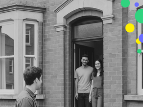 A young heterosexual couple are stood in their open front door of their early victorian terrace house, with a bay window. they are looking out at a neighbour who is speaking to them, holding a piece of paper.