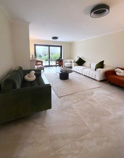 Modern living room with white sofas, rug, coffee table, and large windows.