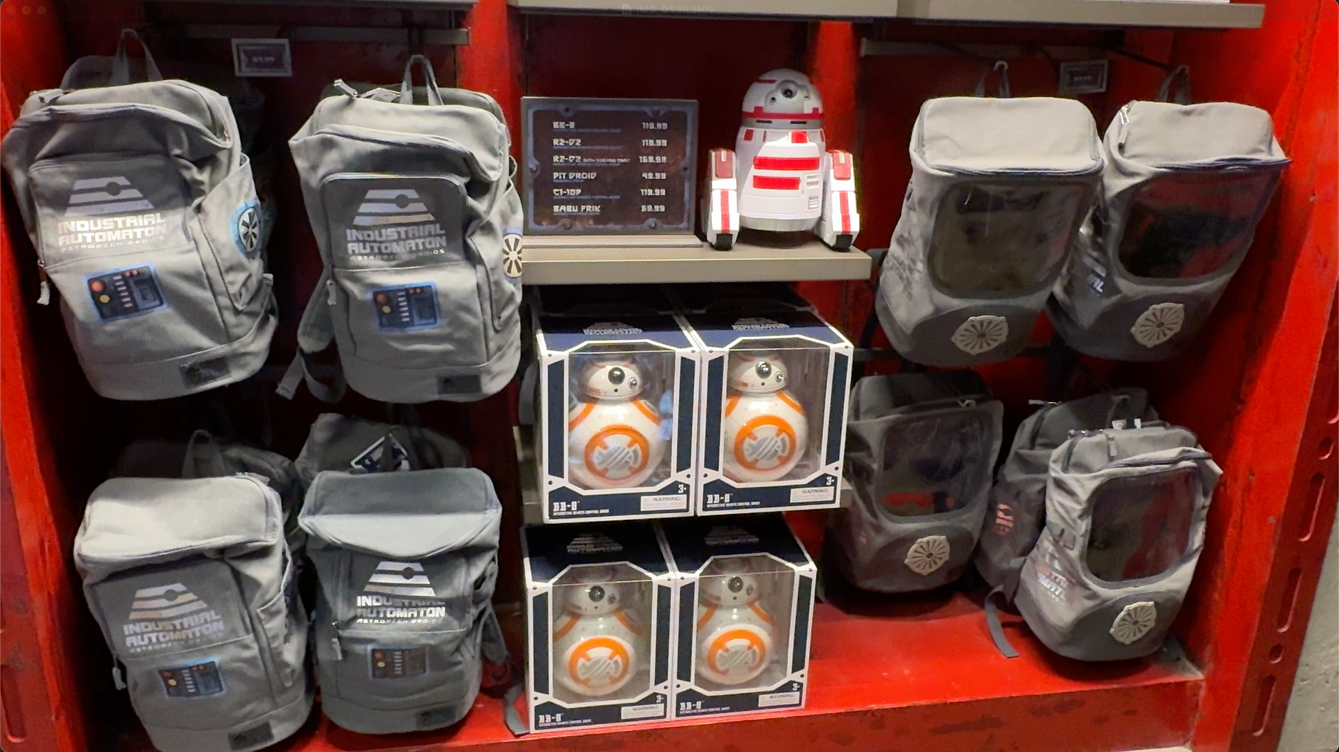 A red wall display showing backpacks and BB 8 droids with a price sign