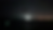 Dark seascape with distant vertical light beam on horizon; scattered clouds and faint city lights glow, reflecting mood of mystery.