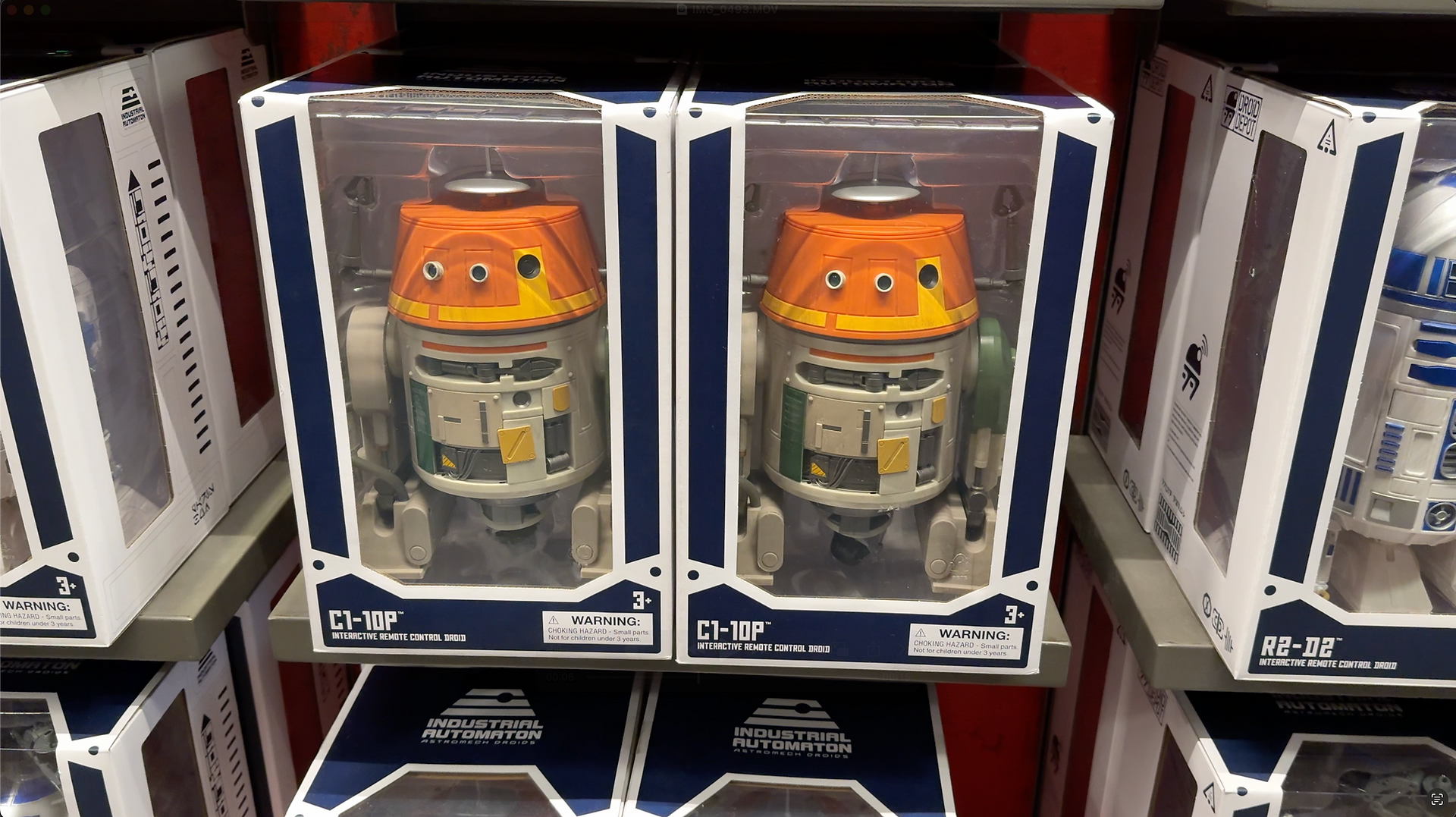 Two C1-10P toy droids in boxes. R2-D2 toy droid is to the right.