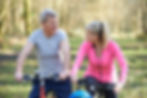a man and woman take a break from biking out on a trail; sitting on their bikes and chatting with each other
