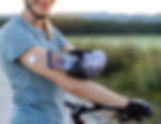 a female biker taking a break from biking to check her blood sugar by scanning her continuous glucose monitor with her phone