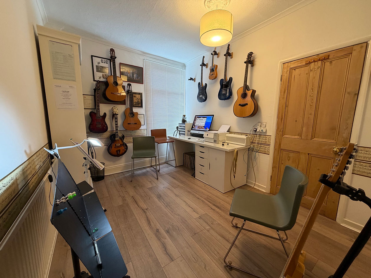 Study room for guitar lessons, guitars hung on the wall and desk with computer