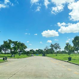A paved main road under a bright, sunny sky at Manila Memorial Park in Dasmariñas, Cavite