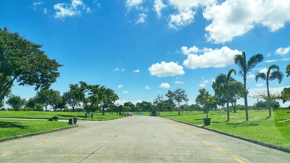 A paved main road under a bright, sunny sky at Manila Memorial Park in Dasmariñas, Cavite