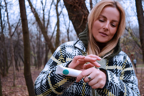 Das Bild zeigt eine Frau vor herbstlichen Bäumen die eine Tube Creme verwendet um Ihre Hände einzucremen