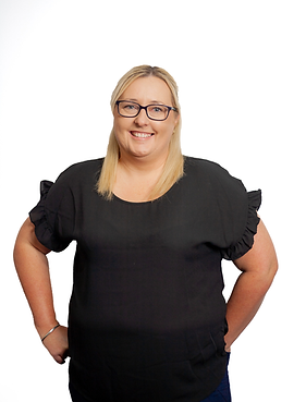 blond woman with glasses wearing black clothes with hands on hips