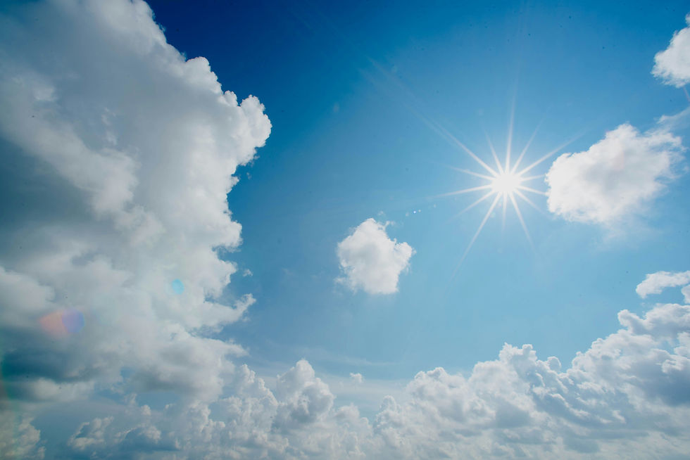 Bright sunburst in a blue sky with large white clouds