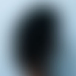 The back of a girl's black curly hair with a blue wall behind