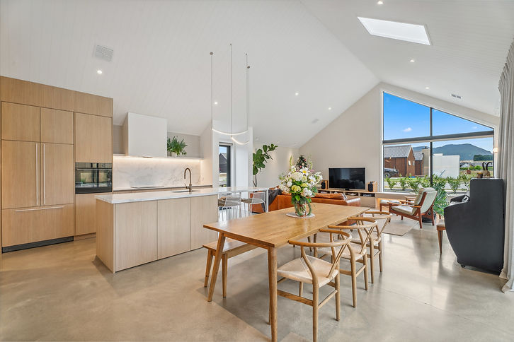 Large kitchen space with large windows, new timber dining table, piano and lounge seating