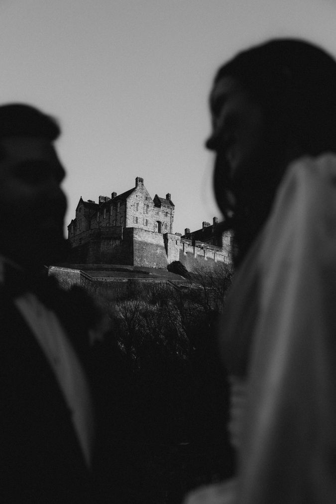 poetic capture of bride and groom glancing at eachother with Edinburgh castle lies in the background by sam mcgregor