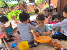 Children using shovels, pails and sifters in sandbox