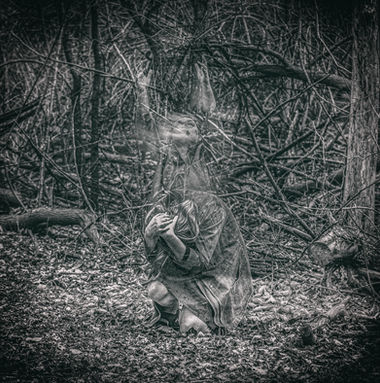 Ghostly figure reaches to sky while hazy figure braces in a crouch down below in hazy woods