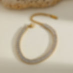 Gold bracelet with sparkling stones on a white surface, elegant design