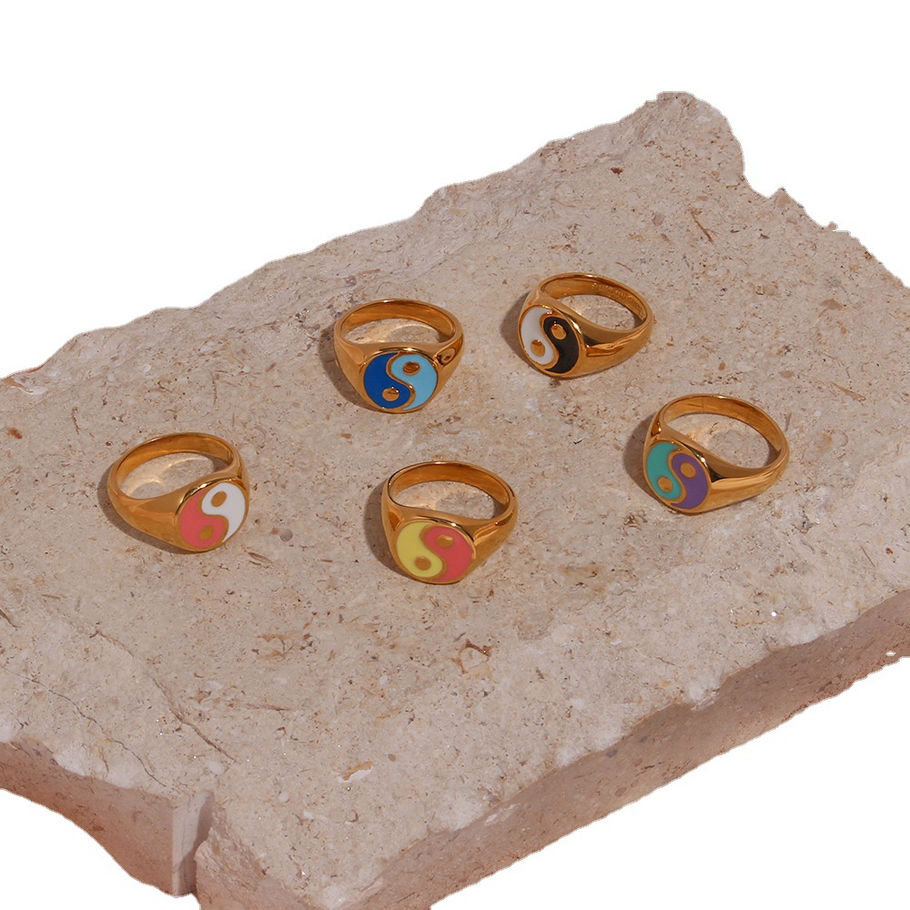 Five gold rings with colorful yin yang symbols on a stone 9to5Jewels