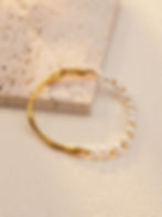 Gold bracelet with pearls and elegant design on a neutral background. 9to5Jewels