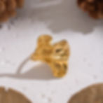 Golden textured ring on white surface, 9to5Jewels jewelry piece with great detail.