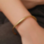 Woman's arm with gold bracelet. Simple gold bangle bracelet. 9to5Jewels.