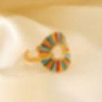 Golden ring with colorful enamel inlay on a soft, white background. 9to5Jewels
