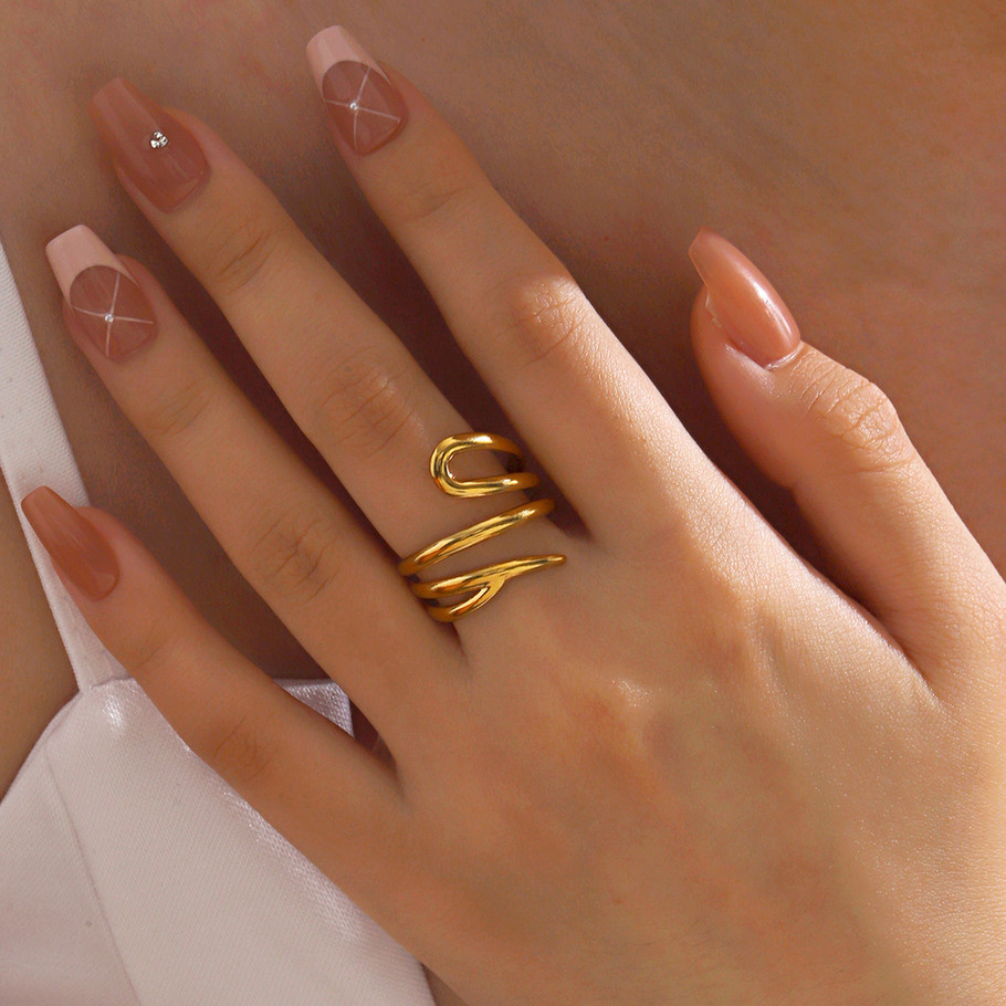 Woman's hand wearing golden ring, 9to5Jewels, with light-colored nail polish.