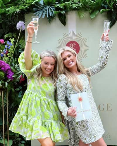 Girls cheering at an event with greenery backdrop