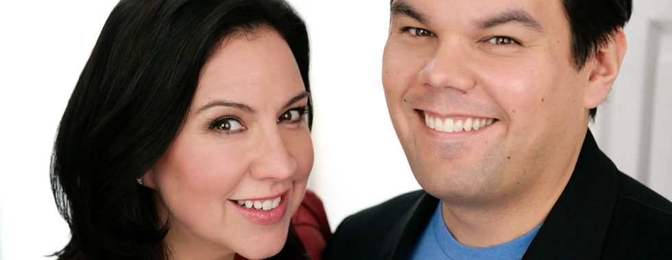 A portrait of Robert Lopez, smiling and posing with a woman, who is also smiling
