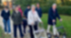 Senioren wandelen buiten met rollators in een park.