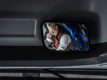 Zoomed in reflection of a bus driver in a rear-view mirror