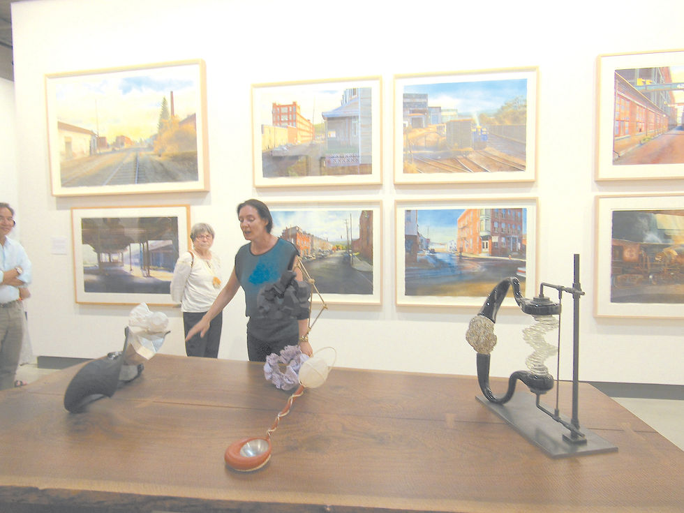 Curator Christina Kee leading a tour showing how each artist elicits a story about Louis-Dreyfus’ relationship to the artist. Kee shows sculptures on the table by John Newman, the watercolors behind are by Matthew Daub.