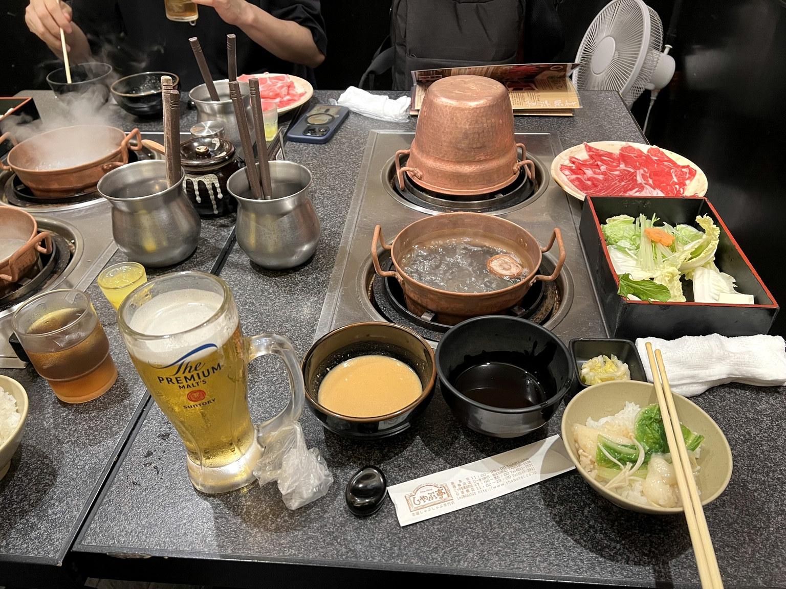 Mesa de shabu-shabu com panelas de cobre e carne