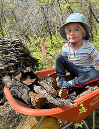 Young child helps to clear branches during the construction of Earth to Sky Accommodations