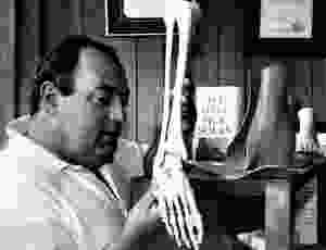 Stewart holding a skeleton leg, looking at the bones of the feet. In the background it says "We Heel Sick Soles"